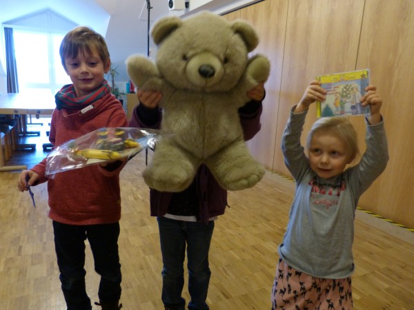 3 Kinder mit Spielzeug und großem Teddybär